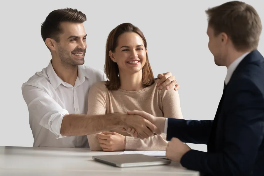 Casal a consolidar crédito, apertando a mão do gestor de crédito.